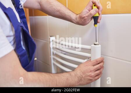 Klempner Montage oder Reparatur eines Handtuchheizkörpers im Badezimmer Stockfoto
