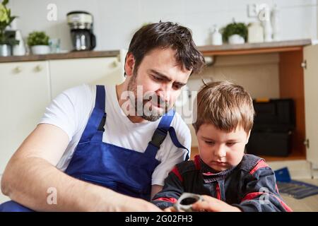 Heimwerker Vater und Sohn wechseln ein defektes Absperrventil ein Das Spülbecken in der Küche Stockfoto