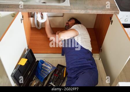 Klempner am Anschluss des Abflusses und der Installation eines Spülbeckens im Küche Stockfoto