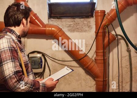 Heimwerker oder Handwerker prüfen Rohre und Kabel im Keller Mit einer Checkliste Stockfoto