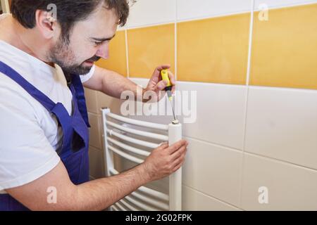 Heizungsinstallator installiert Heizkörper aus Heizung im Badezimmer Stockfoto