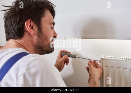 Heimwerker montieren oder reparieren den Heizkörper eines Heizkörpers in Das Badezimmer Stockfoto