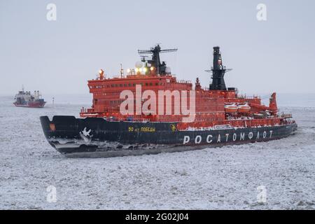 Sabetta, Region Tjumen, Russland - 4. April 2021: Der 50 ließ Pobedy Eisbrecher zieht in Eis. Bewölkt, leichter Schnee fällt. Stockfoto