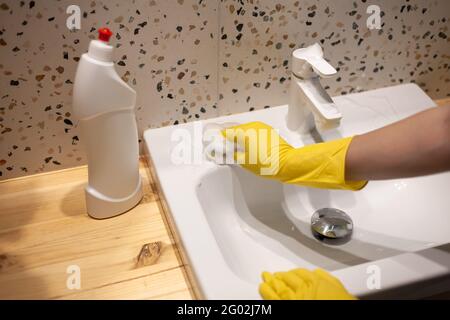 Weibliche Hände Reinigung Badezimmer Waschtisch in Schutzhandschuhen an Zu Hause Stockfoto