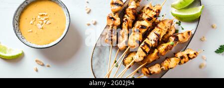 Hähnchen gegrillte Satay Spieße serviert mit Limette und Erdnusssauce, Banner. Asiatisch-thailändisches Essen. Stockfoto