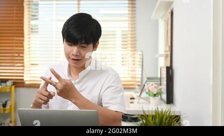 Junger Geschäftsmann mit Videoanruf mit Geschäftspartner auf Laptop und Diskussion Arbeitsprojekt online. Stockfoto