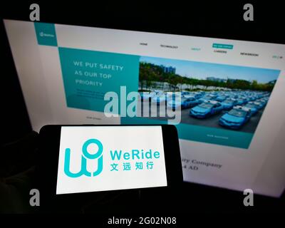 Person, die Mobiltelefon mit dem Logo des chinesischen autonomen Fahrers WeRide auf dem Bildschirm vor der Business-Webseite hält. Konzentrieren Sie sich auf die Telefonanzeige. Stockfoto