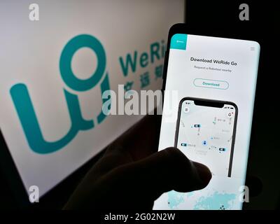 Person, die Mobiltelefon mit Webseite des chinesischen autonomen Fahrers WeRide auf dem Bildschirm vor dem Logo hält. Konzentrieren Sie sich auf die Mitte des Telefondisplays. Stockfoto