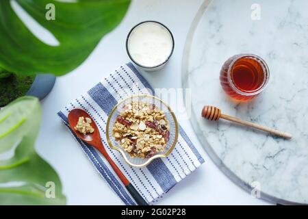 Cerealien-Frühstück in Schüssel, Brot und Honig auf weißem Hintergrund Stockfoto