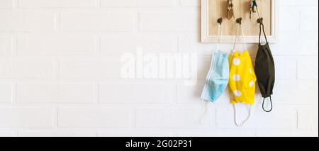 Baum schützende Gesichtsmasken auf den Schlüsseln Organizer Haken auf dem Loft-Design weißen Hintergrund Ziegelwand im Hausflur. Gesundheitskonzept während C Stockfoto