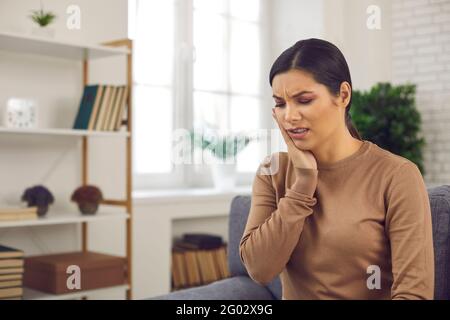 Unglückliche junge Frau, die an Zahnschmerzen leidet und die Wange berührt Grimasse der Schmerzen Stockfoto
