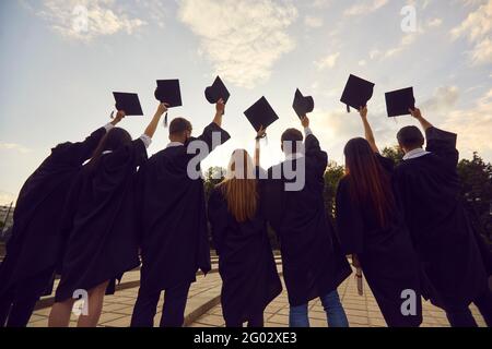 Rückansicht einer Gruppe von Hochschulabsolventen mit akademischen Kappen Bevor sie in die Luft geworfen werden Stockfoto