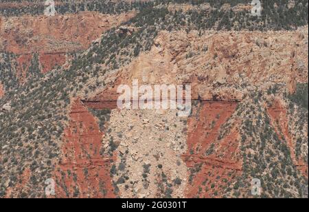 Aufnahme aus einem Hubschrauberfenster. Panorama-Luftaufnahme einer Wand im Inneren des Grand Canyon. Beachten Sie die Muster von kontrastierenden roten Sandsteinen und grünen Bäumen. Stockfoto