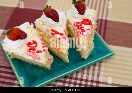 Nahaufnahme von weißen Vanilleschwamm-Kuchenscheiben auf einem blauen Teller Stockfoto