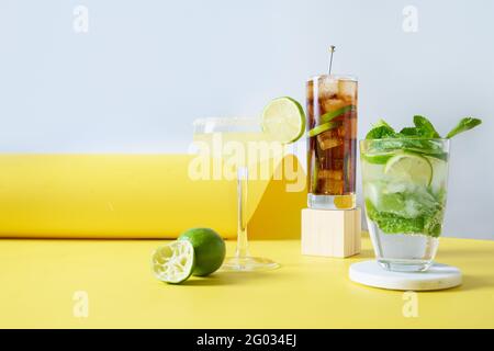 Klassischer Mojito, cuba Libre, margarita Cocktail mit Limette und Zitrone im modernen Stillleben auf gelbem Hintergrund. Drei Sommer Frische Getränk fo Stockfoto
