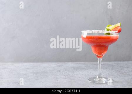 Erdbeer Margarita Cocktail garnieren Limette isoliert auf grauem Hintergrund mit Kopierraum. Frische alkoholischer Margarita Cocktail aus Erdbeere pur Stockfoto
