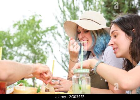 Eine Gruppe von glücklichen Freunden, die Spaß haben und in einem Park essen. Picknick an einem sonnigen Sommertag. Stockfoto