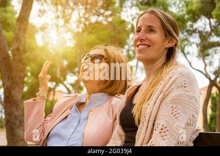 Glückliche Familie, die am Wochenende Spaß hat.Ältere Mutter und ihre Erwachsene Tochter unterhalten sich und genießen gemeinsam Zeit im Naturpark bei Sonnenuntergang. Stockfoto