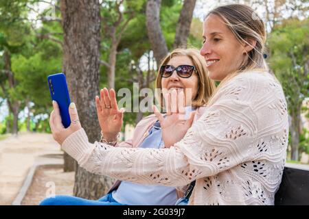 Glückliche Familie Spaß im Freien mit Smartphone.Ältere Großmutter und jung Tochter aussehendes Smartphone, das ein Selfie macht oder ein Video macht Rufen Sie uns an Stockfoto