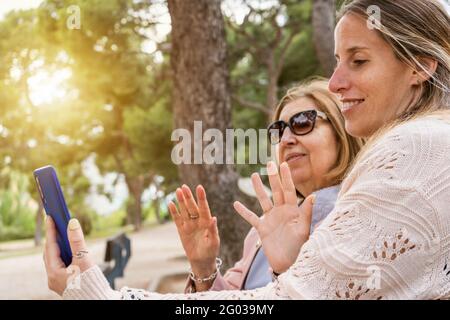 Glückliche Familie Spaß im Freien mit Smartphone.Ältere Großmutter und jung Tochter aussehendes Smartphone, das ein Selfie macht oder ein Video macht Rufen Sie uns an Stockfoto