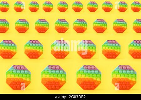 Nahtlos abnehmende Muster der sensorischen Anti-Stress-Pop IT-Spielzeug auf einem gelben Hintergrund. Pop-Bubble Drücken. Trendy beliebtes Spielzeug. Stockfoto