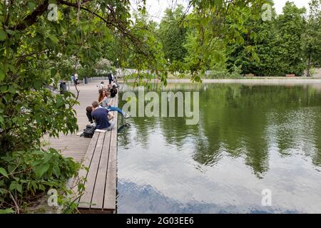 Moskau, Russland - Mai, 2021, Gorki Central Park of Culture and Leisure. Die Menschen ruhen auf dem Pier in der Nähe des künstlichen Teiches Stockfoto
