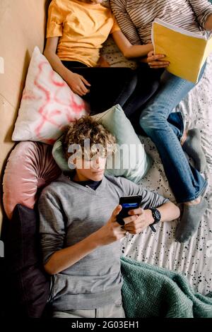 Junge mit Smartphone, während er im Schlafzimmer lag Stockfoto