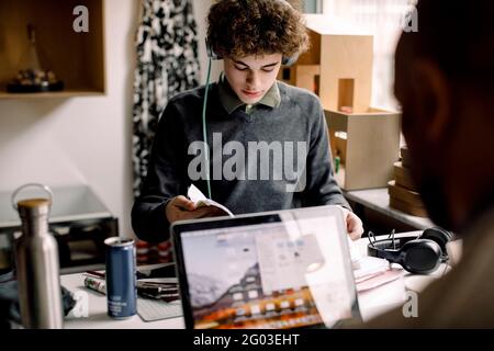 Teenager studiert, während der Vater am Schreibtisch am Laptop arbeitet Stockfoto