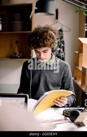 Junge, der Kopfhörer trägt, während er zu Hause studiert Stockfoto