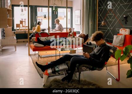 Junge und Vater verwenden Technologien im Wohnzimmer mit Schwester und Mutter im Hintergrund Stockfoto