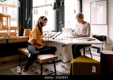 Geschäftsfrau, die zu Hause arbeitet, während ihre Tochter mit einem digitalen Tablet lernt Stockfoto