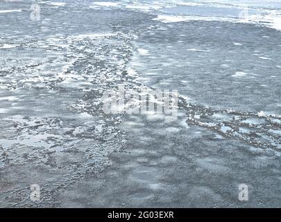 Gebrochenes Eis von dunkelblauer Farbe auf dem Fluss. Zerkleinerte Eisbrocken auf dunklem Wasser. Abstrakter ICE-Hintergrund. Blauer Hintergrund mit Rissen auf dem Eis-Surfa Stockfoto