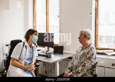 Ärztin, die während des COVID-19 eine ältere Patientin konsultiert Stockfoto