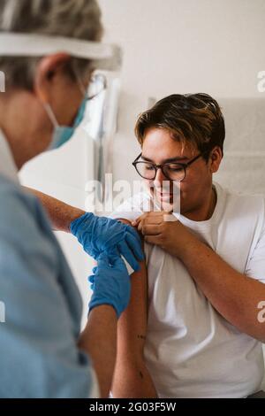 Leitende medizinische Expertin, die einen männlichen Patienten während des COVID-19 injiziert Stockfoto