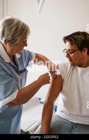 Leitende Ärztin, die einen männlichen Patienten in der medizinischen Klinik injiziert Stockfoto