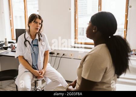 Ärztin, die mit dem Patienten während der Konsultation in der medizinischen Klinik Stockfoto