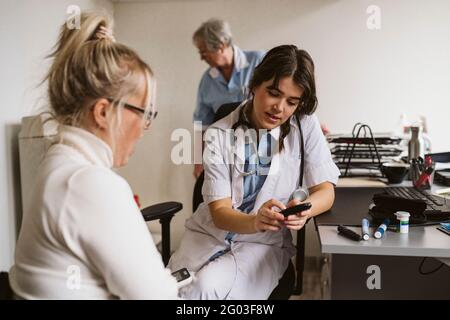 Weibliche Gesundheitsarbeiterin, die in der medizinischen Klinik über ein Glaukommessgerät sprach Stockfoto