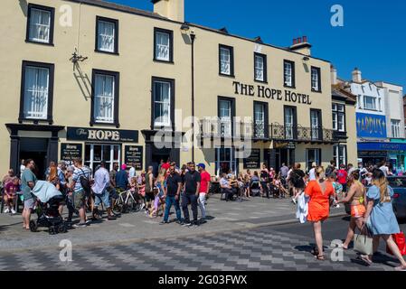 Southend on Sea, Essex, Großbritannien. Mai 2021. Das warme, sonnige Wetter hat die Menschen am Montag an den Feiertagen in die Küstenstadt gelockt. Unternehmen am Meer sind mit Kunden auf dem Bürgersteig vor dem Hope Hotel Strandcafe beschäftigt und Menschen, die vorbei gehen Stockfoto