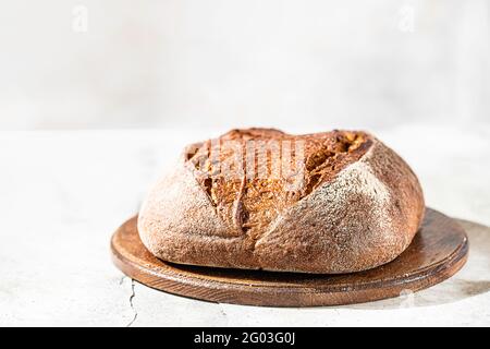 Frisch gebackenes Roggenbrot auf hellem Beton-Hintergrund. Ort für Ihren Text. Frisch gebackenes Sauerteigbrot. Gebäck. Selektiver Fokus Stockfoto