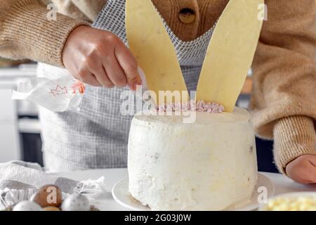 Nahaufnahme eines zugeschnittenen Bildes von Frau, die Kuchen in der Küche zu Hause backen und dekorieren. Stockfoto