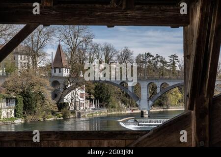 Blick durch die Holzbrücke über den Reuss zum weißen Turm namens Katzenturm und Eisenbahnviadukt in Bremgarten im Frühling. Kanton Aargau in SWI Stockfoto