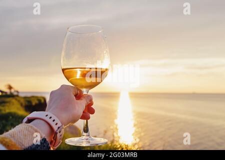 Frau hält bei Sonnenuntergang ein Glas Roséwein in der Hand Stockfoto