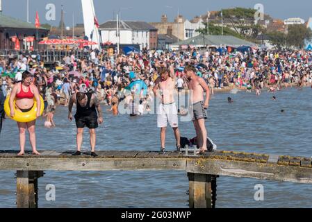 Southend on Sea, Essex, Großbritannien. Mai 2021. Das warme, sonnige Wetter hat die Menschen am Montag an den Feiertagen in die Küstenstadt gelockt. Die Strände sind voll und Teenager nutzen einen Steg, um ins Meer zu springen. Männer trinken Stockfoto