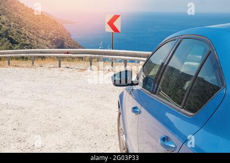 Blaues Auto hielt am Straßenrand in der Nähe des Meeres an sonnigen Tag. Stockfoto