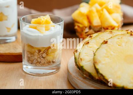 Köstliches Ananasdessert. Frühstücksdessert mit Hafergranola, griechischem Joghurt und Ananas in Glasschichten mit Zutaten frisch saftig gehackt Stockfoto