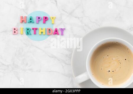 Happy Birthday Text aus bunten Holzbriefen mit Tasse Kaffee Stockfoto