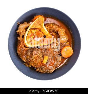 Draufsicht auf eine Portion Ossobuco (mit Gemüse, Wein und Brühe geschmortes Rindfleisch-Shin) in einer grauen Schüssel, isoliert auf weißem Hintergrund Stockfoto