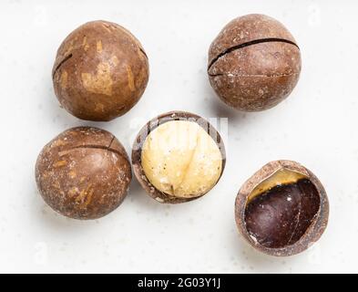 Nur wenige gesägte und geschälte Macadamianüsse schließen sich auf grau an Keramikplatte Stockfoto