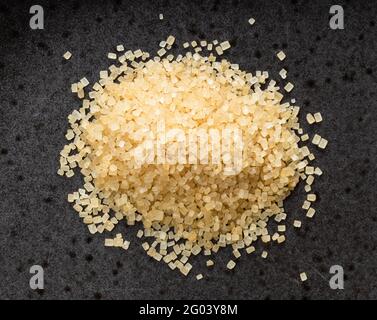 Draufsicht auf Stapel von demerara braunem Rohrzucker in der Nähe Auf schwarzer Keramikplatte Stockfoto