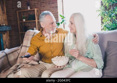 Foto von glücklich fröhlich grauhaarigen Rentner Rentner Paar sitzen Couch gute Laune Fernsehen drinnen im Haus Stockfoto